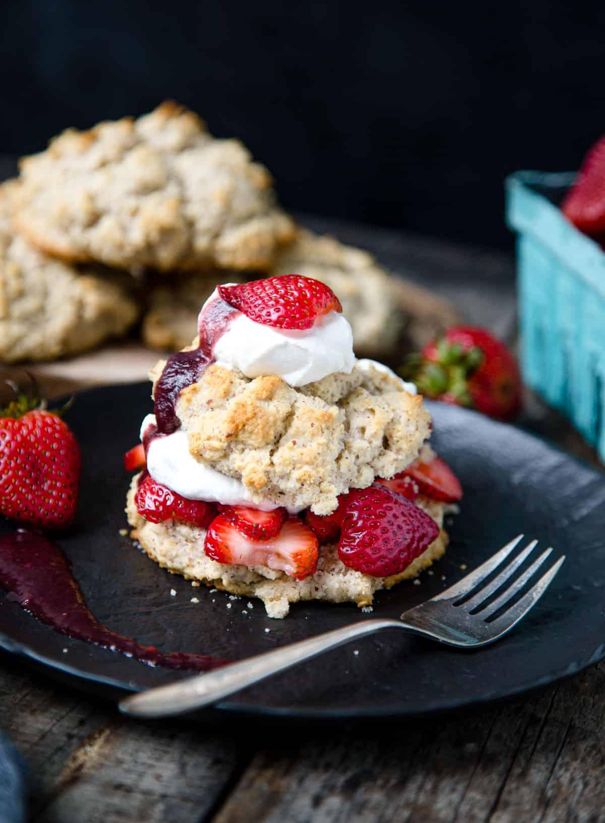 **Shortcake di fragole affumicate su biscotti** 2 Smoked Strawberry Shortcake su un piatto nero con una forchetta