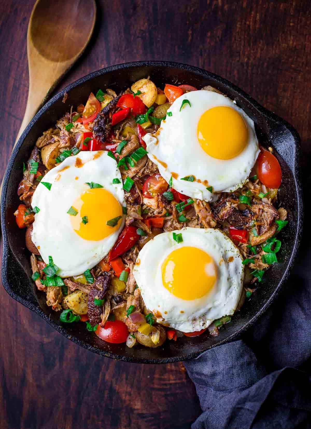 **Padellata di Maiale Sfilacciato per Colazione** 2 Hash di maiale sfilacciato per la colazione in padella di ghisa con uova sopra.