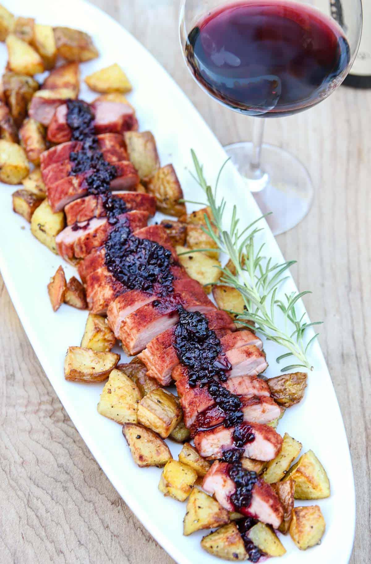 Filetto di Maiale Affumicato con Salsa Affumicata di More al Bourbon 2 Filetto di maiale affumicato con salsa ai lamponi e bourbon su un piatto da portata, pronto per essere servito