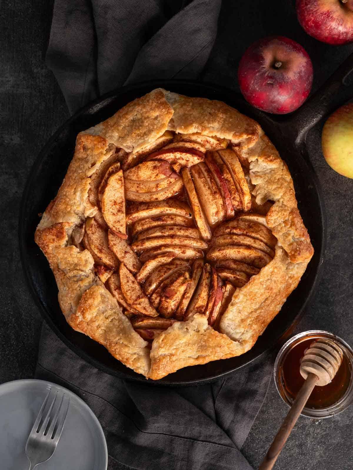 Galette alle Mele Grigliate 2 Una galette di mele alla griglia su un piatto circondata da mele fresche.