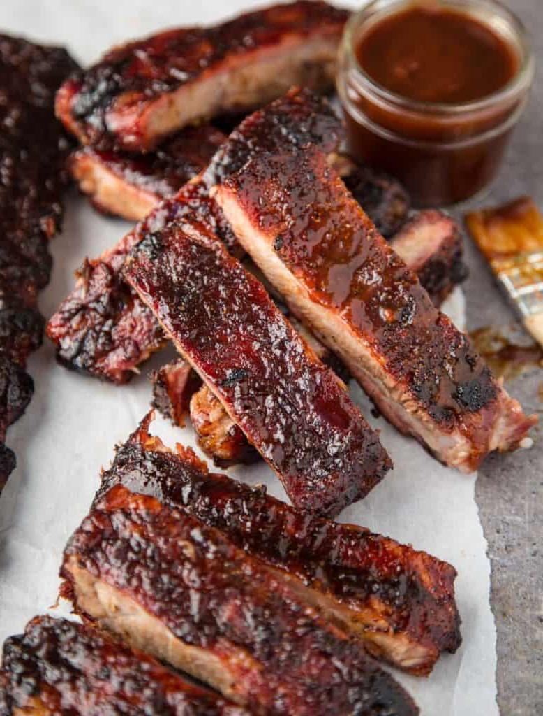 Migliori Tecniche e Ricette di Barbecue da Padroneggiare 2 Costine di maiale affumicate e affettate su un piatto, preparate con un grill a pellet.