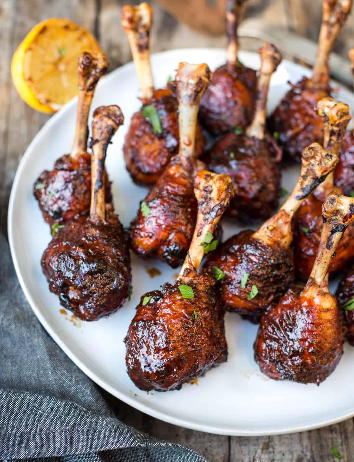 Fusi di Pollo a Lecca-lecca alla Griglia con Glassa BBQ Piccante 2 Pollo Lollipops Grigliati su un piatto bianco