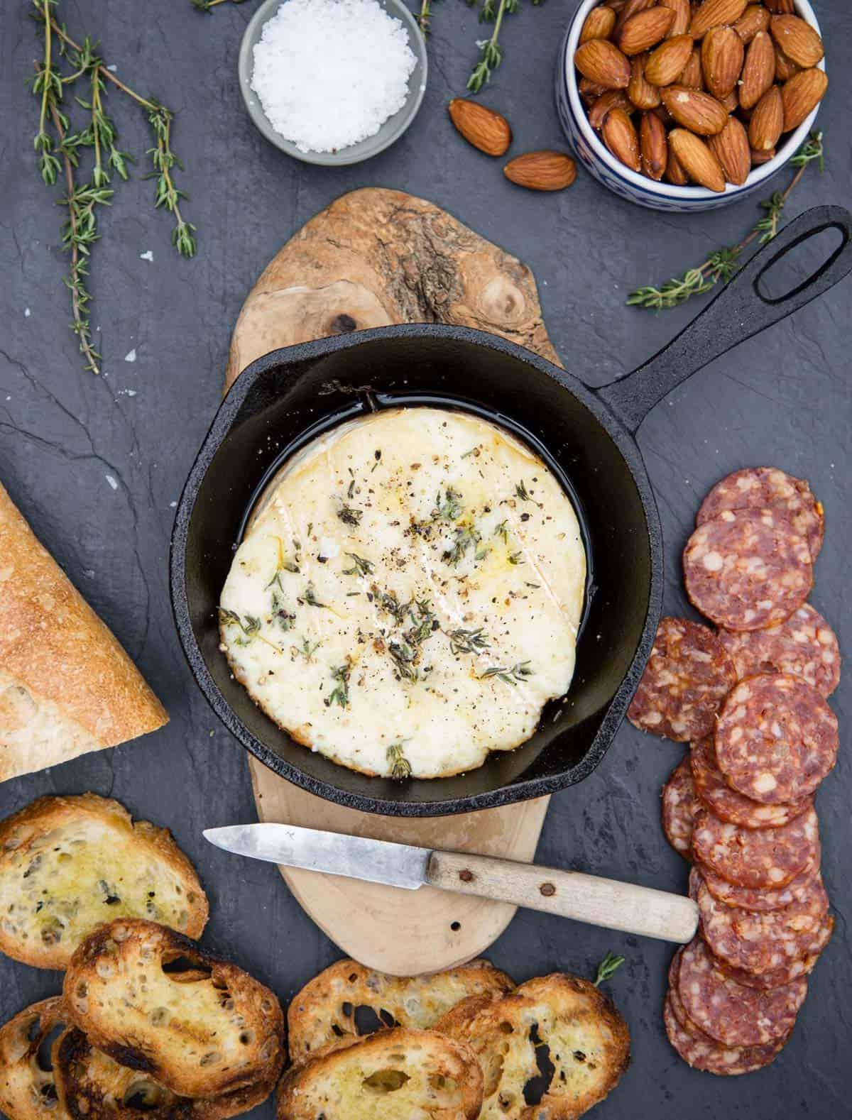 **Brie al Forno con Vino alla Griglia** 2 Un tagliere di formaggi con brie grigliato, fette di baguette, mandorle e salame
