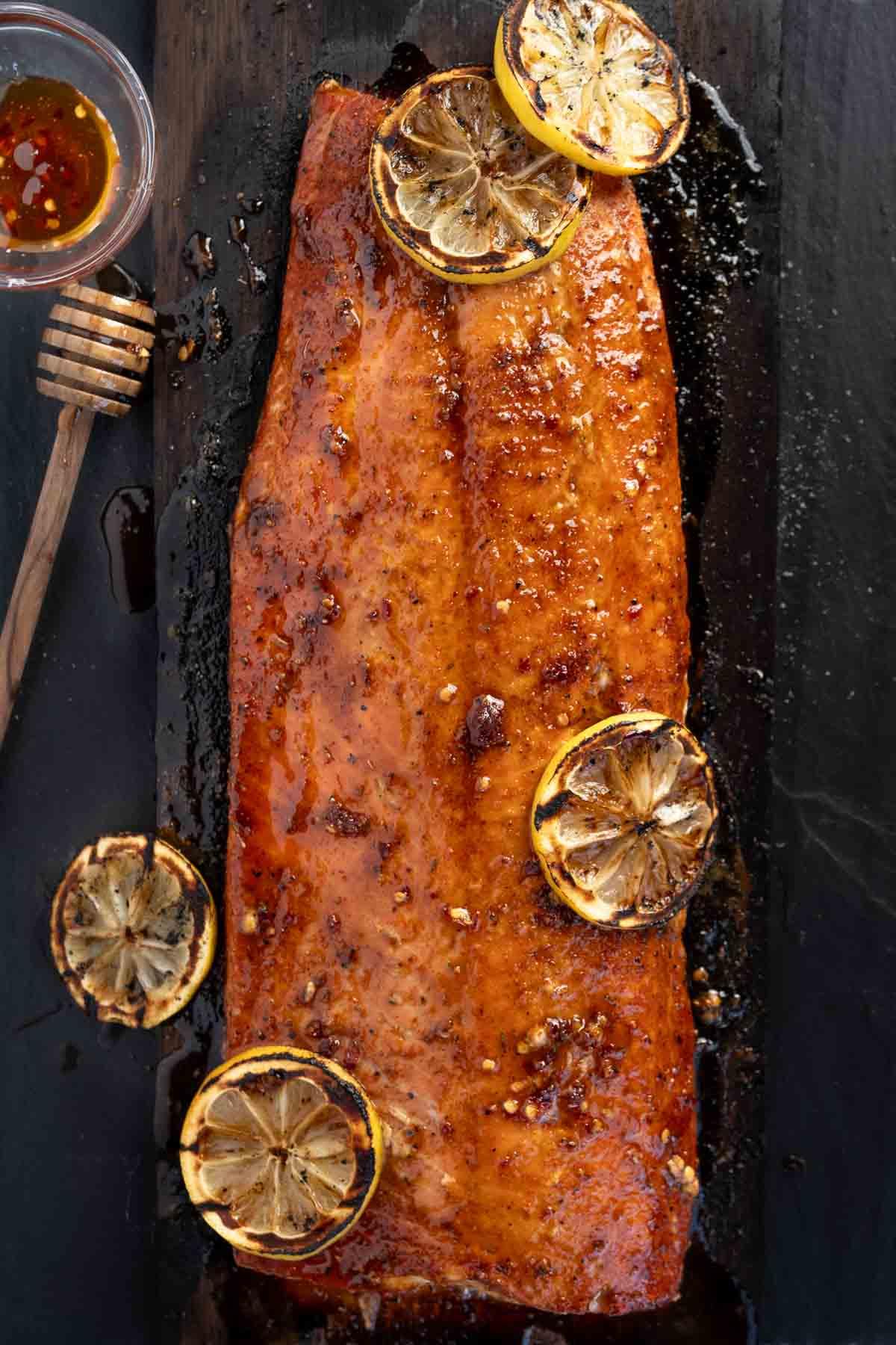 Salmone Grigliato al Miele Piccante 2 Salmone Grigliato al Miele Piccante su una tavola di cedro con fette di limone.