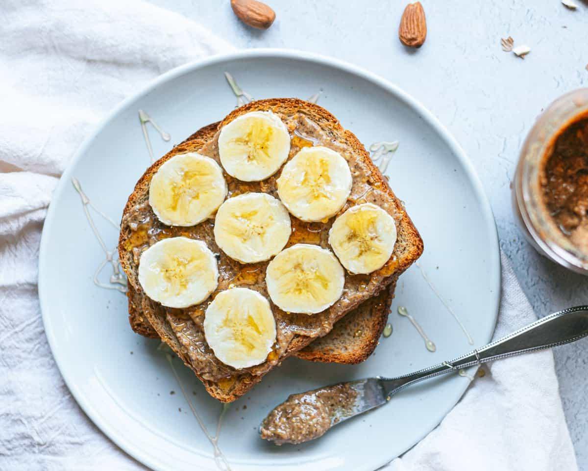 Toast al burro di mandorle affumicato 2 Un piatto con toast ricoperto di burro di mandorle, fette di banana e miele