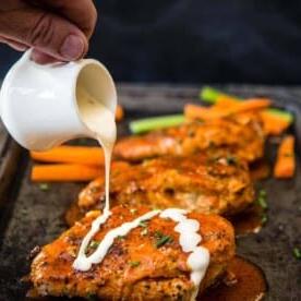 Petto di pollo farcito alla Buffalo alla griglia 11 Petti di pollo ripieni alla Buffalo su un vassoio con salsa ranch versata sopra.