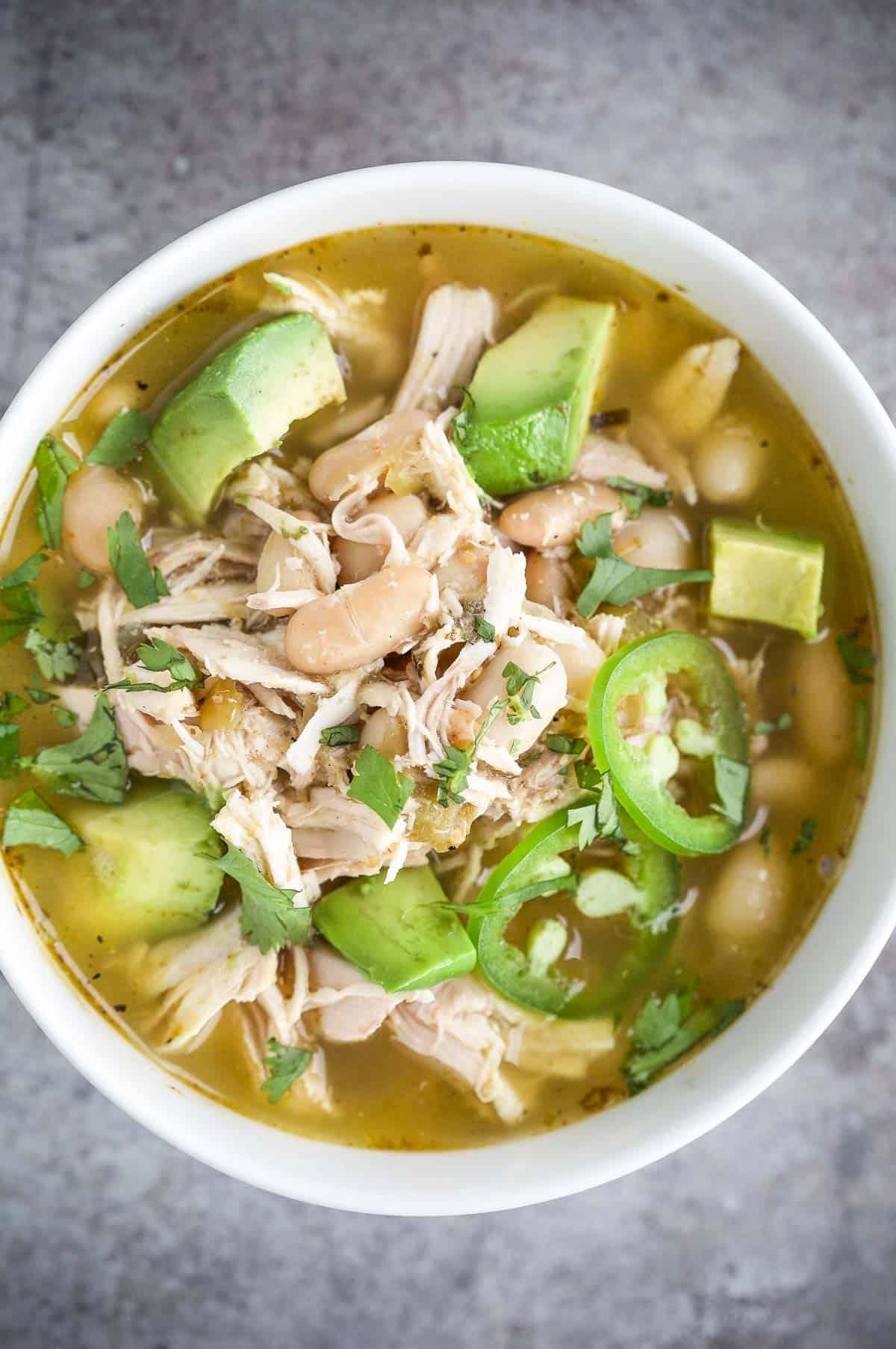 Ricetta Zuppa di Pollo Affumicato alla Salsa Verde 3 Una ciotola di zuppa di pollo affumicato con salsa verde guarnita con fette di avocado e jalapeño