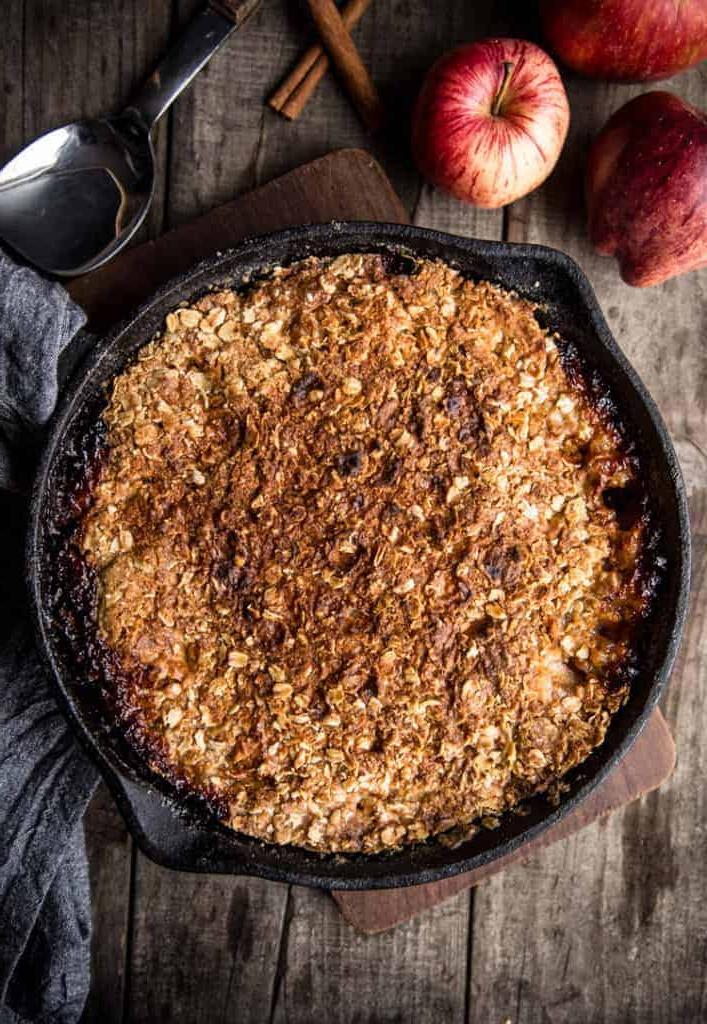 **Crumble di Mele Grigliate** 3 dessert alla griglia in una teglia in ghisa con mele e cannella a lato