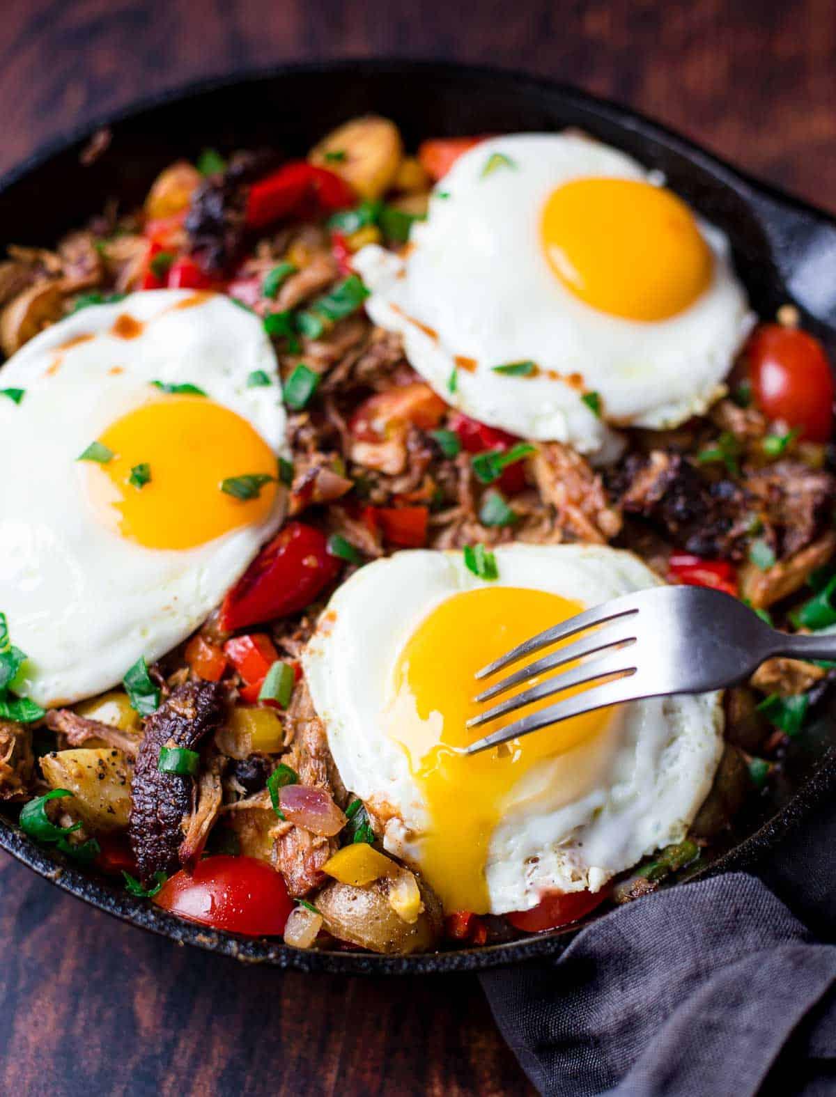 **Padellata di Maiale Sfilacciato per Colazione** 4 Hash di maiale sfilacciato con uova in una padella.