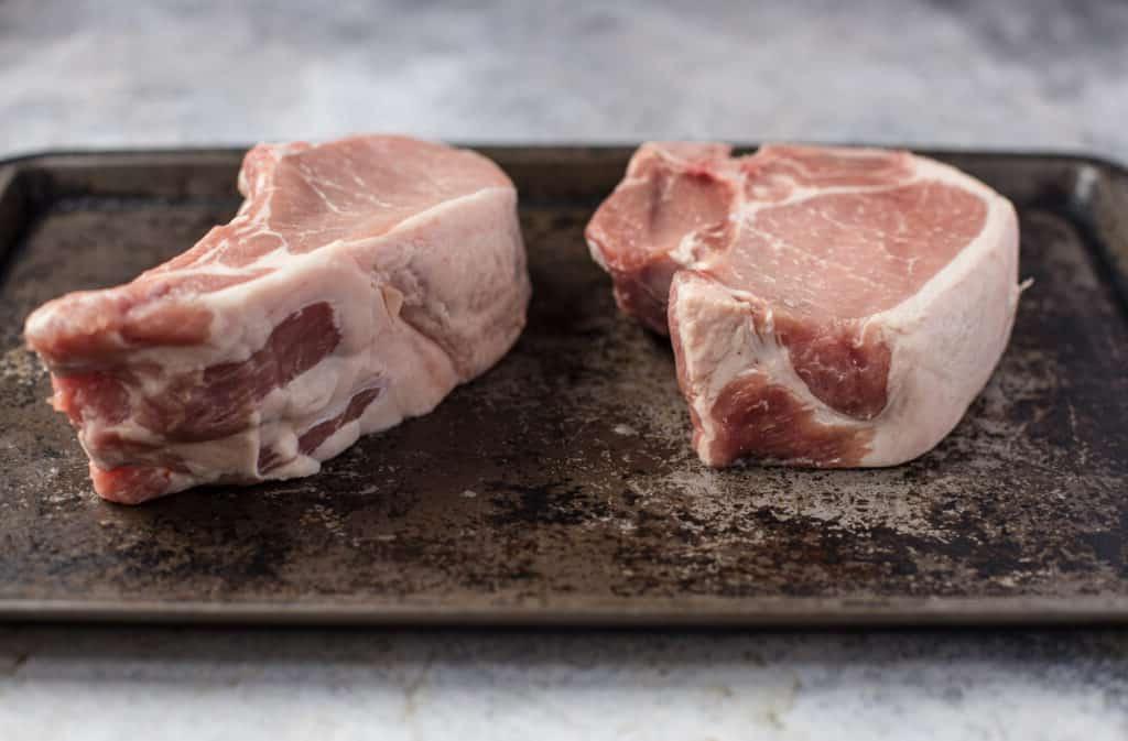 Costolette di Maiale alla Griglia con Salsa al Vino Rosso 4 Angolo laterale di costolette di maiale con osso spesse due pollici. Una costoletta centrale e una costoletta di costola.