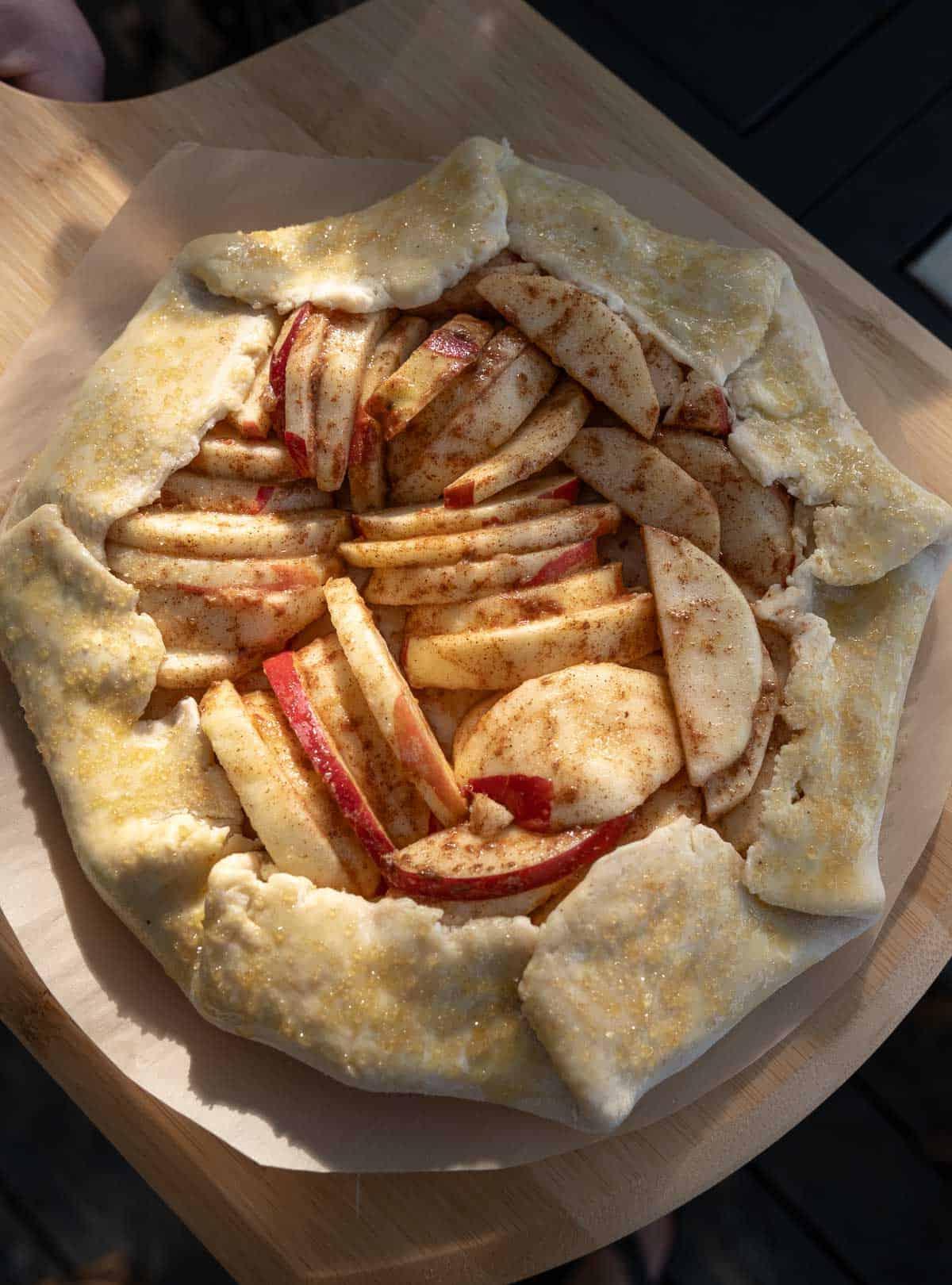 Galette alle Mele Grigliate 4 Galette di mele preparata su carta forno, pronta per essere cotta, con il ripieno di mele disposto al centro.