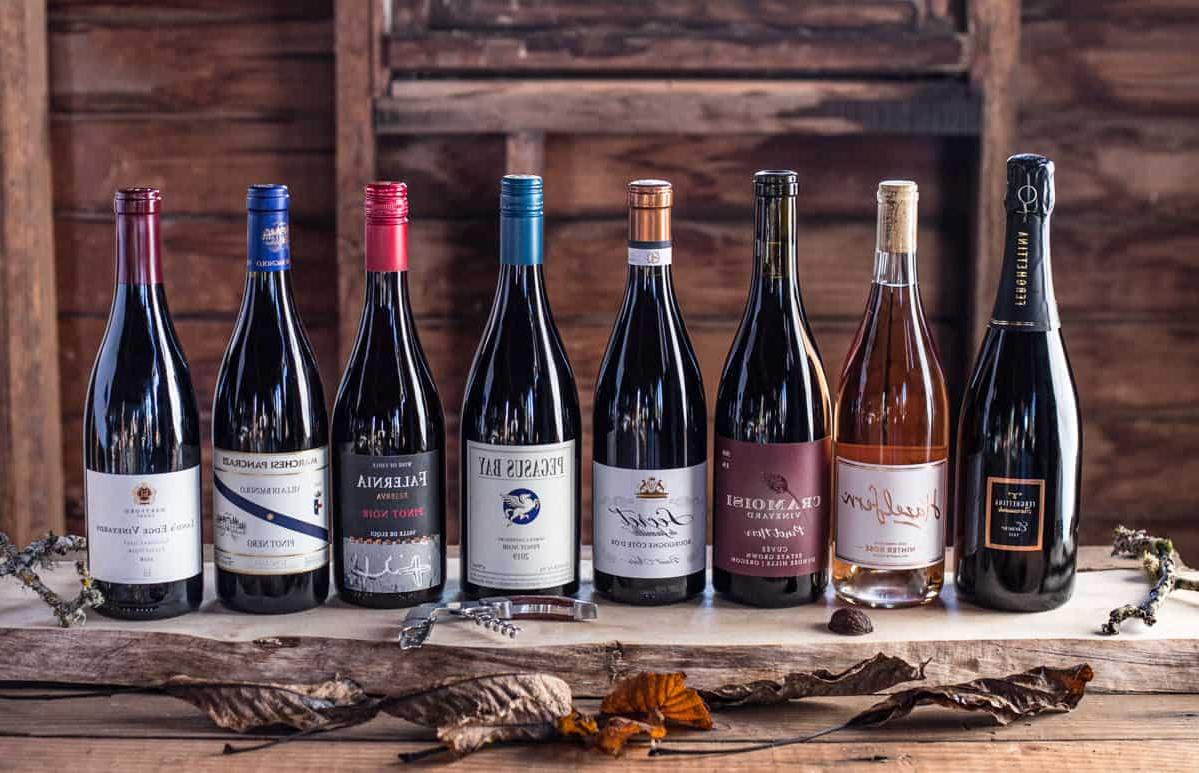 Guida al Pinot Noir 4 Diverse bottiglie di Pinot Nero in stili diversi su un tagliere di legno.