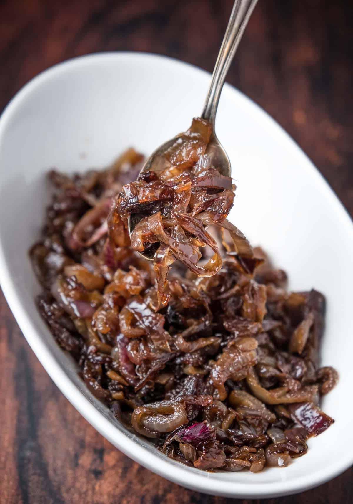 Cipolle caramellate in una ciotola, sollevate con un cucchiaio.