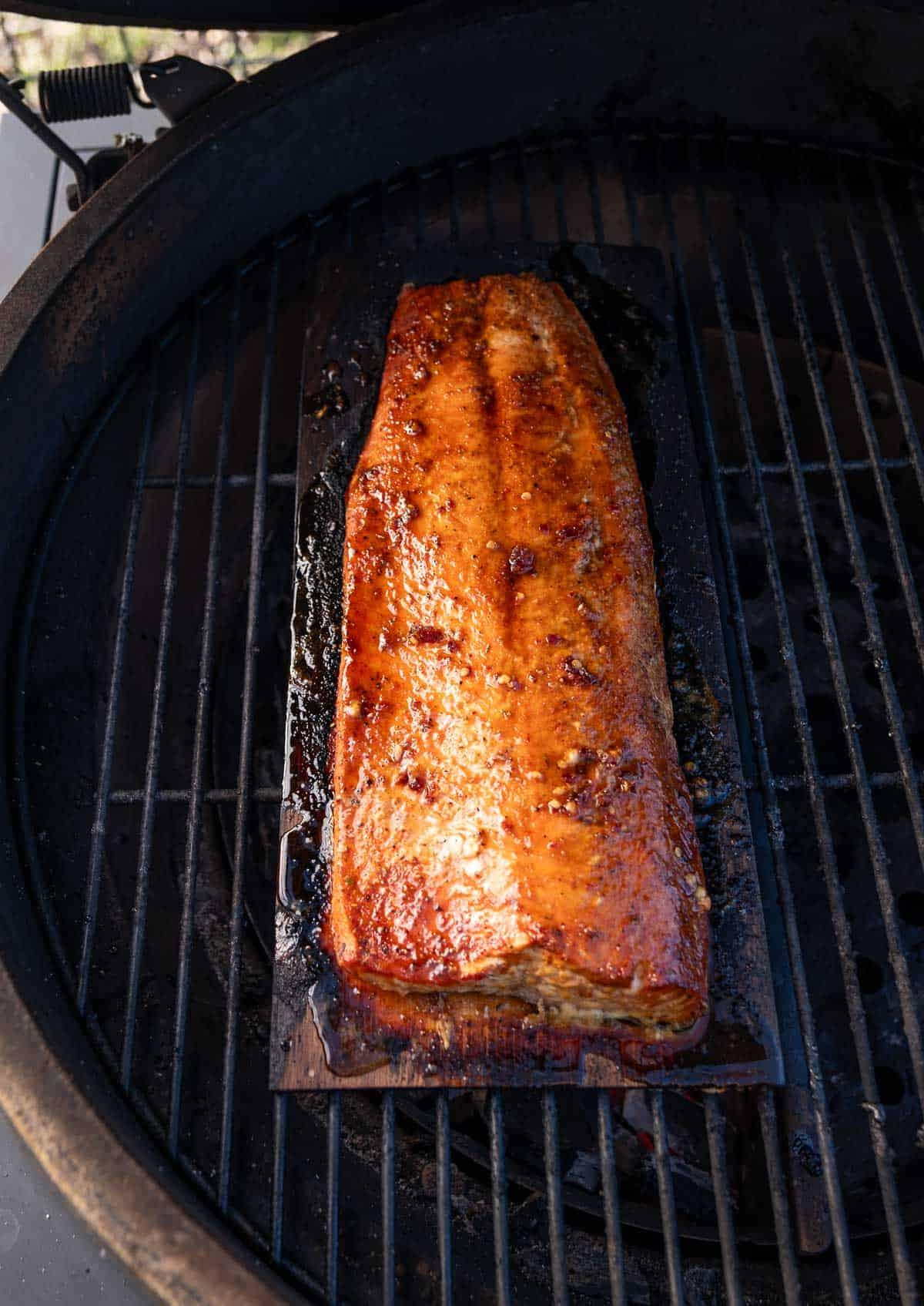Salmone Grigliato al Miele Piccante 4 Salmone al Miele Piccante in cottura su una tavola di cedro sulla griglia a fuoco diretto.