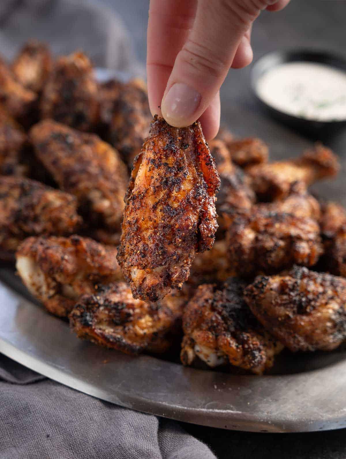 Ricetta per Rub Secco per Alette 4 Una mano che tiene un'ala di pollo croccante con rub secco