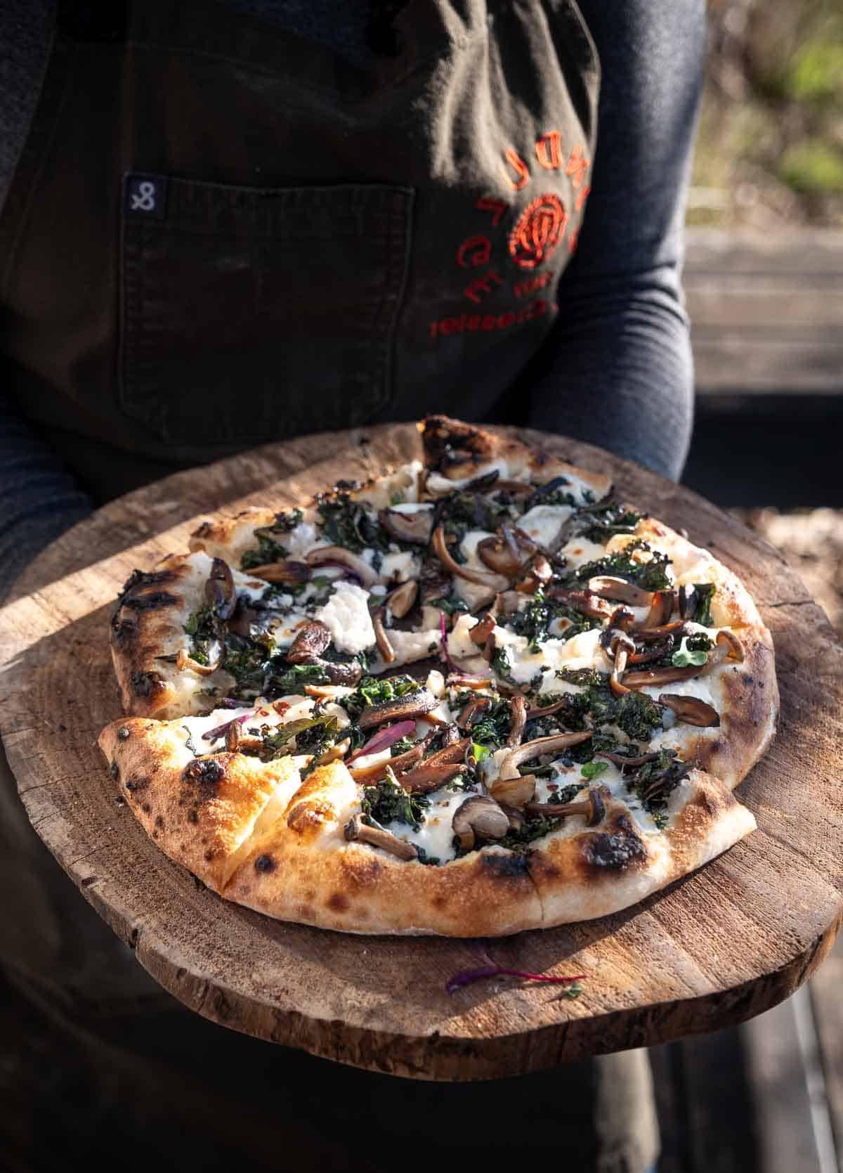 Recensione Forno Pizza Solo Stove Pi Prime – Un Ottimo Forno Pizza Sotto i $400 5 Una pizza al cavolo nero cotta su una pala di legno.