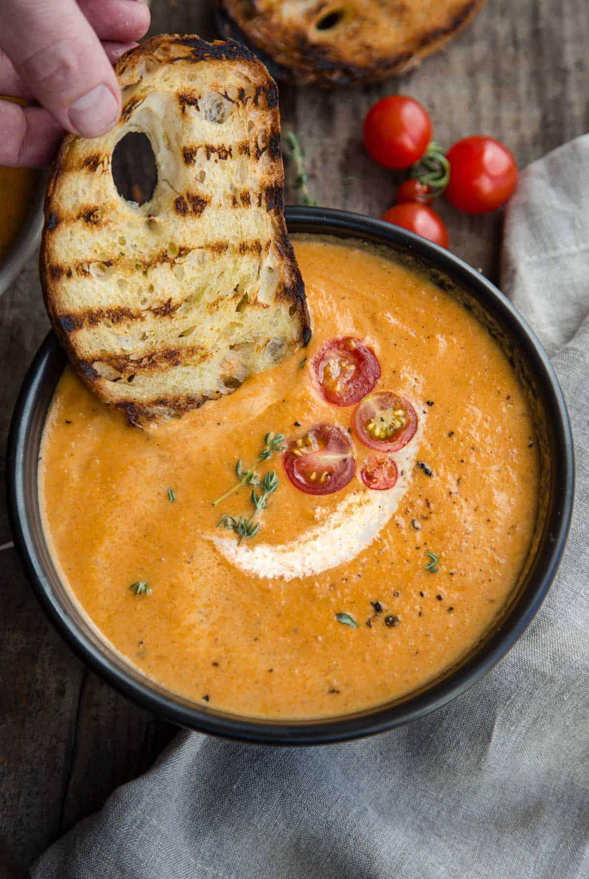 Vellutata di Pomodoro Affumicato 5 Una ciotola di bisque di pomodoro affumicato con pane tostato immerso nella zuppa.