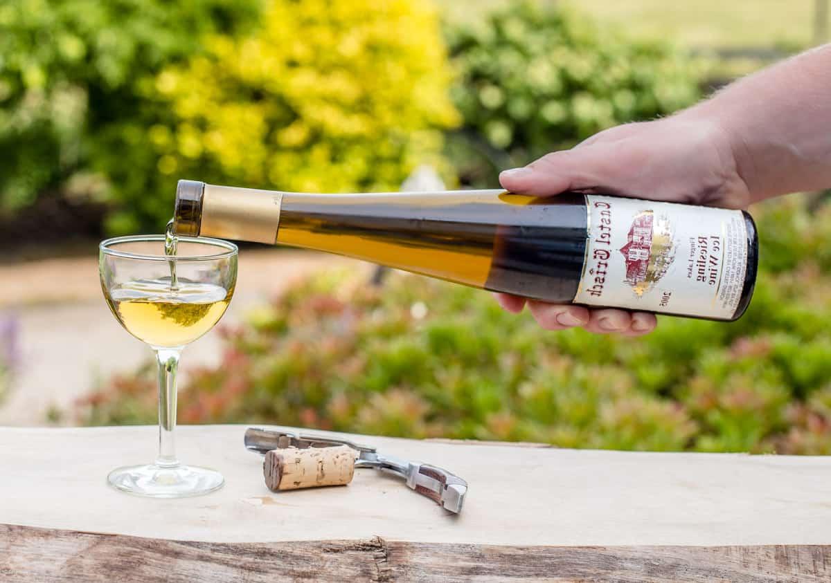 Guida al Vino Riesling 5 Versare una bottiglia di vino di ghiaccio (Eiswein) in un bicchiere, un tipo di Riesling dolce e concentrato da dessert.