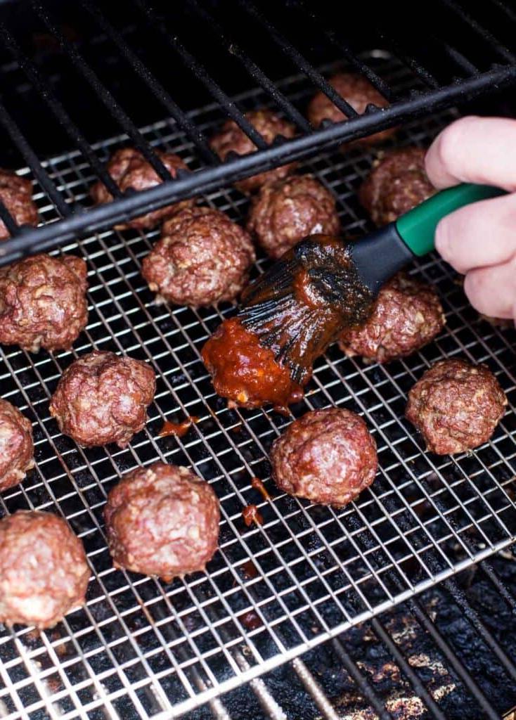Glassando polpette BBQ con un pennello in silicone su una griglia a pellet.