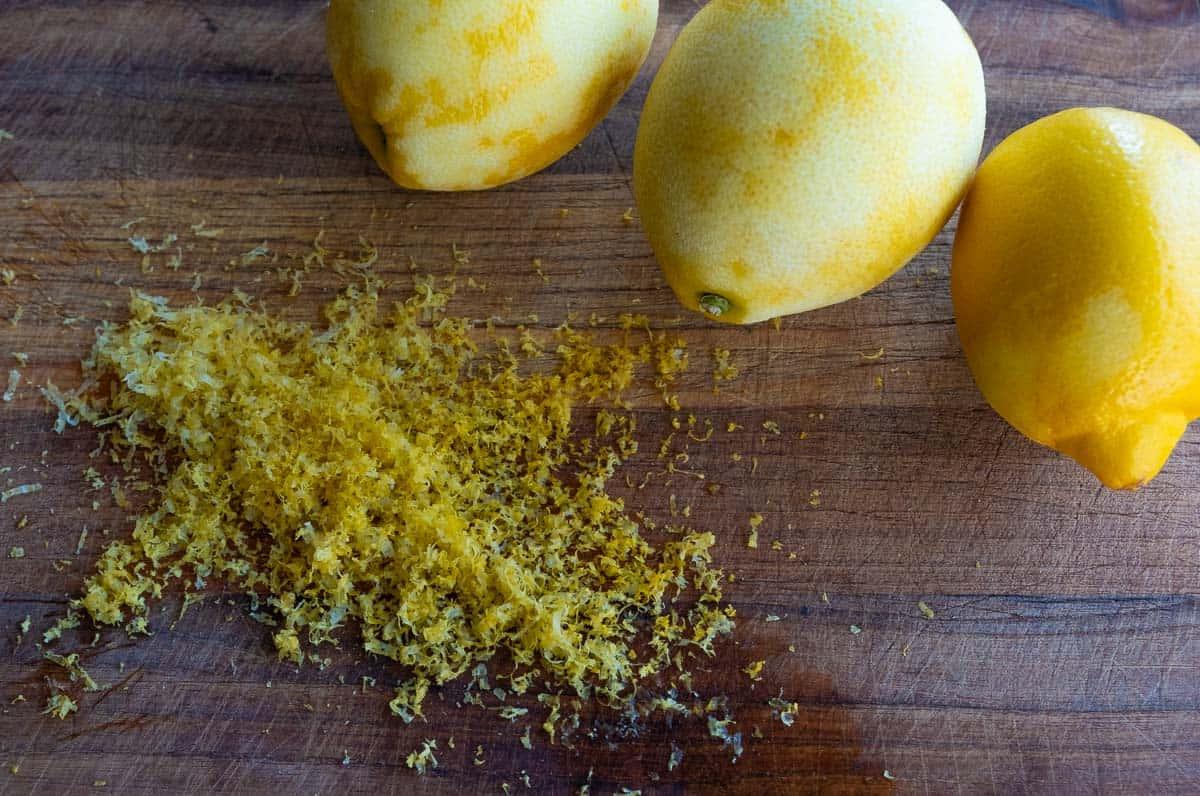 Tre limoni su un tagliere con scorza di limone fresca.