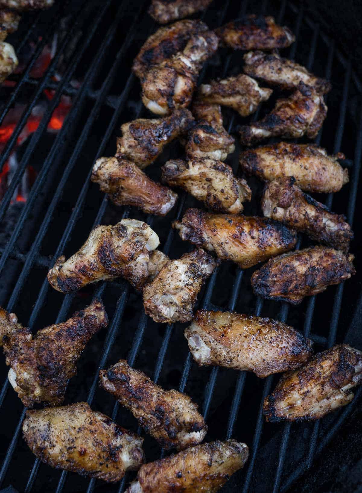 Ali di pollo in cottura su una griglia.