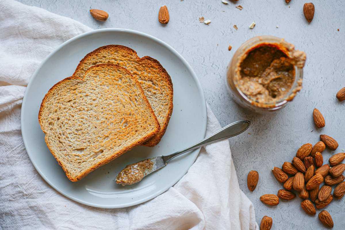 Toast al burro di mandorle affumicato 5 Un piatto con toast secco, mandorle e un barattolo di burro di mandorle