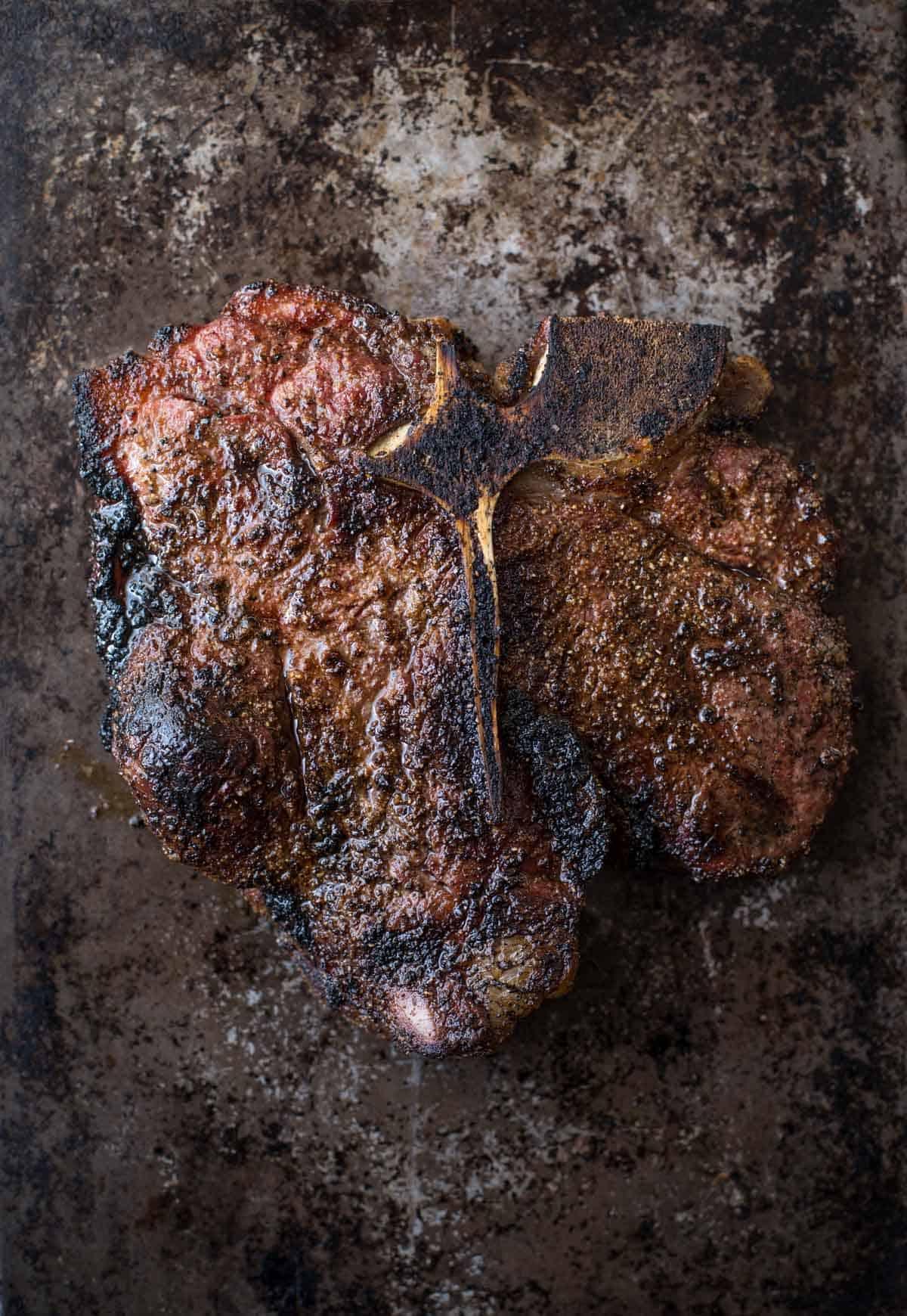 Bistecca Porterhouse Alla Griglia – Cottura Inversa 6 Una bistecca alla porterhouse grigliata che riposa su un piatto.