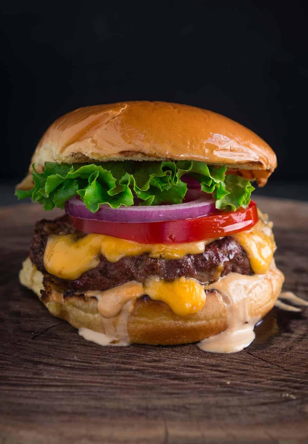 Ricetta dell'Hamburger Affumicato con Formaggio 6 Cheeseburger affumicato classico americano su un tagliere.
