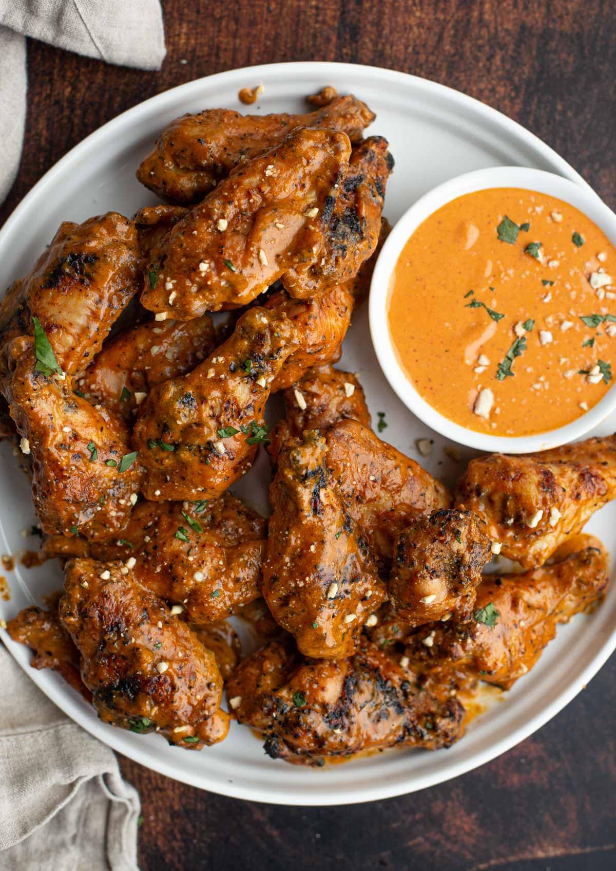 Temperatura del Pollo – La Guida Definitiva per sapere quando è pronto 6 Ali di pollo alla griglia con salsa di arachidi piccante su un piatto con salsa da intingere
