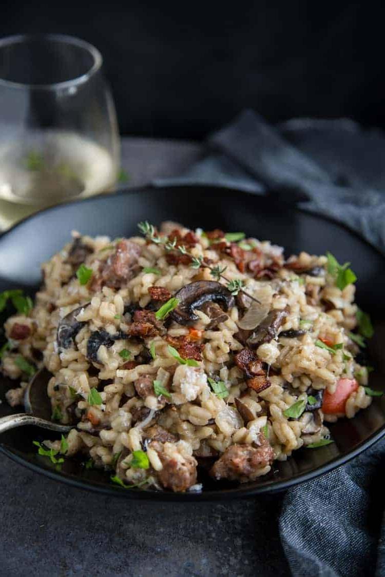 Risotto con Salsiccia Affumicata e Funghi 6 Una ciotola di risotto fatto in casa con salsiccia affumicata, funghi e pancetta, abbinata a un bicchiere di vino.