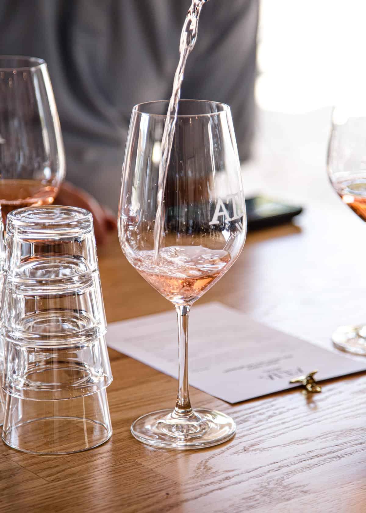 Regione Vinicola del Lago Chelan 7 Versando un bicchiere di Rosé di Alta Cellars in un calice da vino, mettendo in evidenza il suo colore invitante.