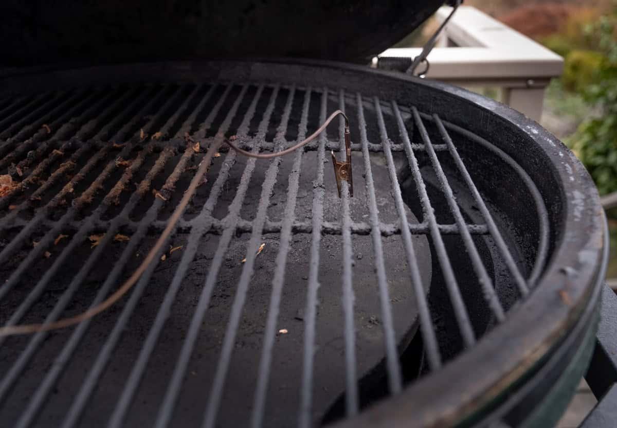 Come Usare il Big Green Egg Egg Genius 7 Un'immagine della clip a coccodrillo dell'Egg Genius per Big Green Egg agganciata a una griglia di cottura sopra la piastra convEGGtor.