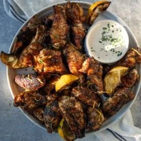 Ali di Pollo al Limone e Pepe Grigliate su un vassoio con una ciotola di salsa ranch fatta in casa.