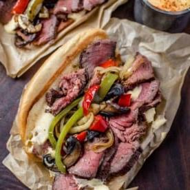 **Panino Grigliato al Cheesesteak** 8 Due panini cheesesteak su un piatto da portata con condimenti.
