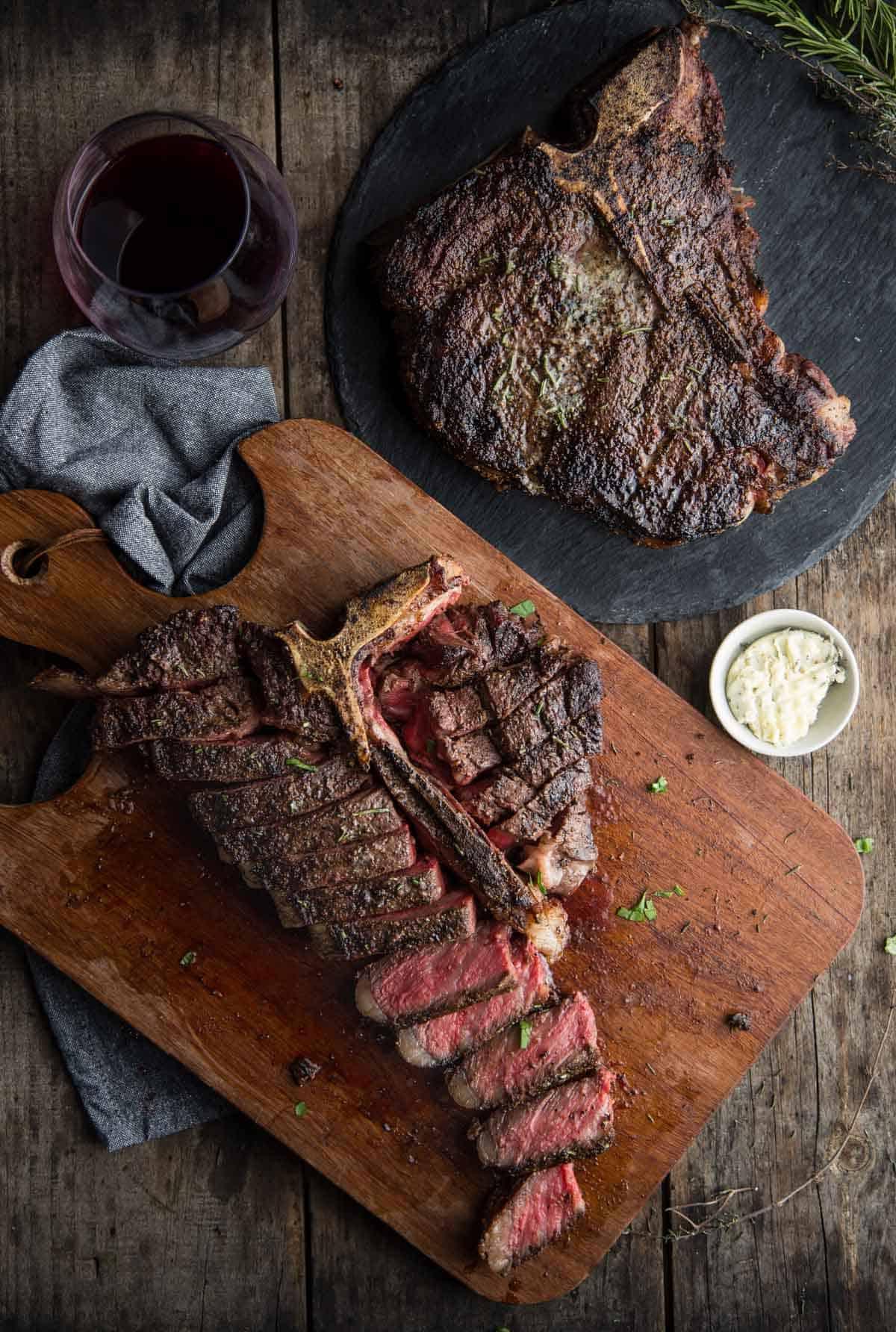 Due bistecche t-bone a riposo su un tagliere.