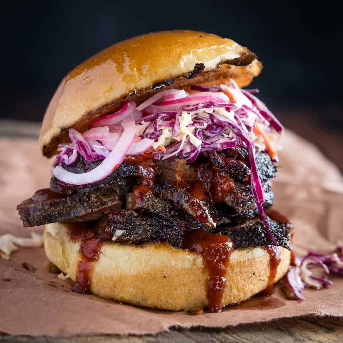 Le 10 migliori ricette con gli avanzi di punta di petto 11 Un Panino BBQ Brisket su un piatto da portata guarnito con coleslaw fatto in casa e salsa bbq
