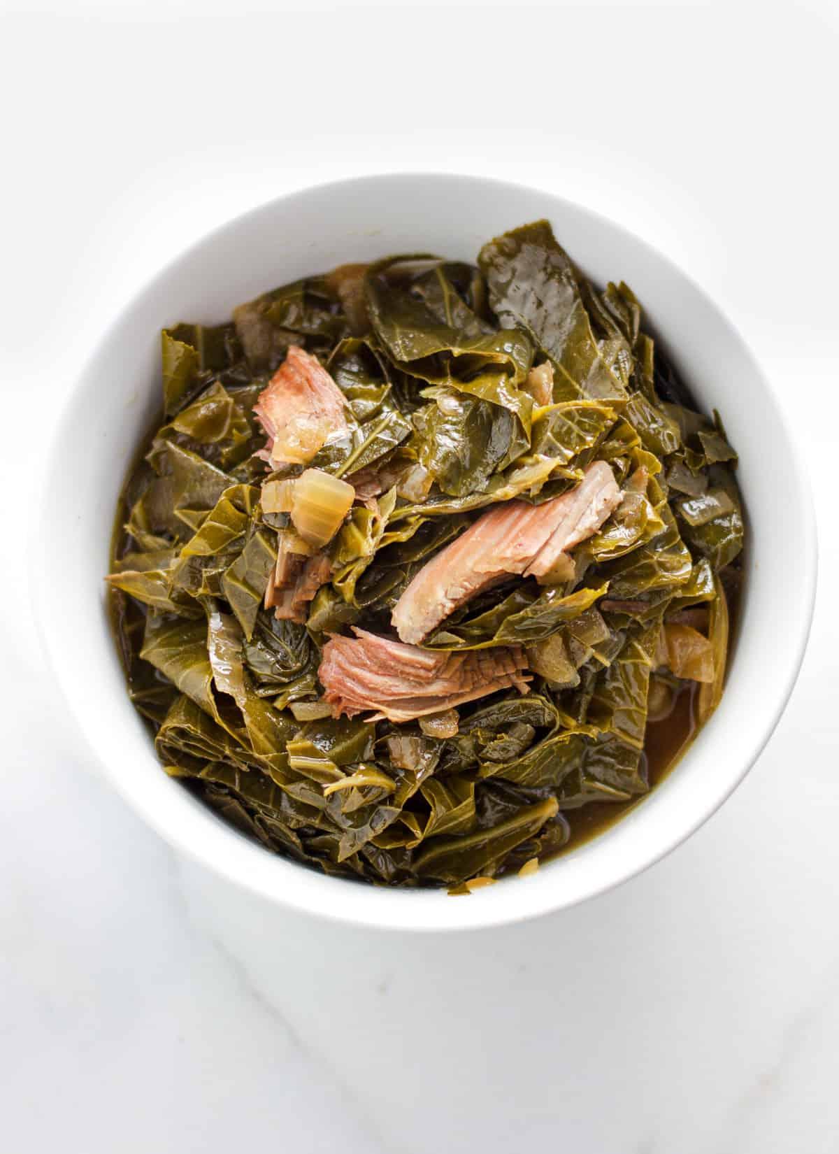 Verdure collard con tacchino affumicato in una ciotola bianca.