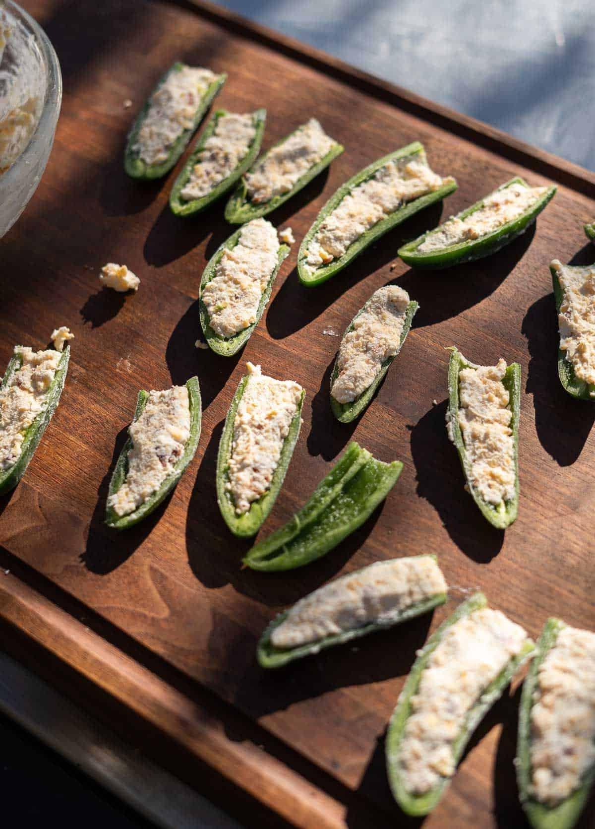 Come Preparare i Peperoncini Jalapeño Ripieni Grigliati 4 Poppers di jalapeño grigliati ripieni su un tagliere pronti per la griglia.