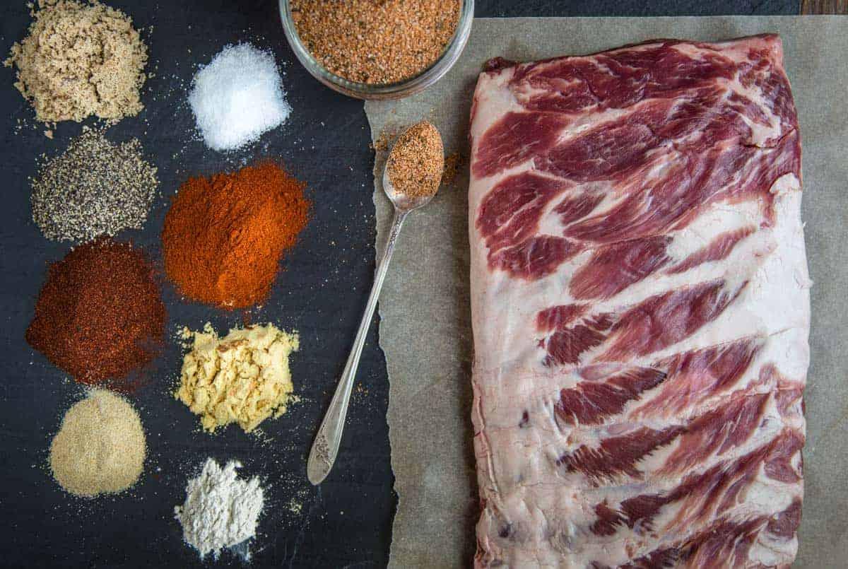 Rub Secco per Costolette (la migliore miscela di Dolce e Salato) 4 Ingredienti per il rub secco per costine di maiale su un vassoio con costine di maiale crude.