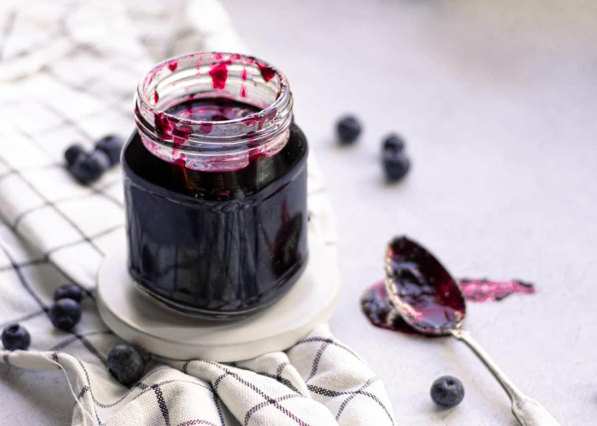 **Sciroppo Semplice di Mirtilli per Cocktail** 5 Sciroppo semplice ai mirtilli su un cucchiaio su un tagliere.