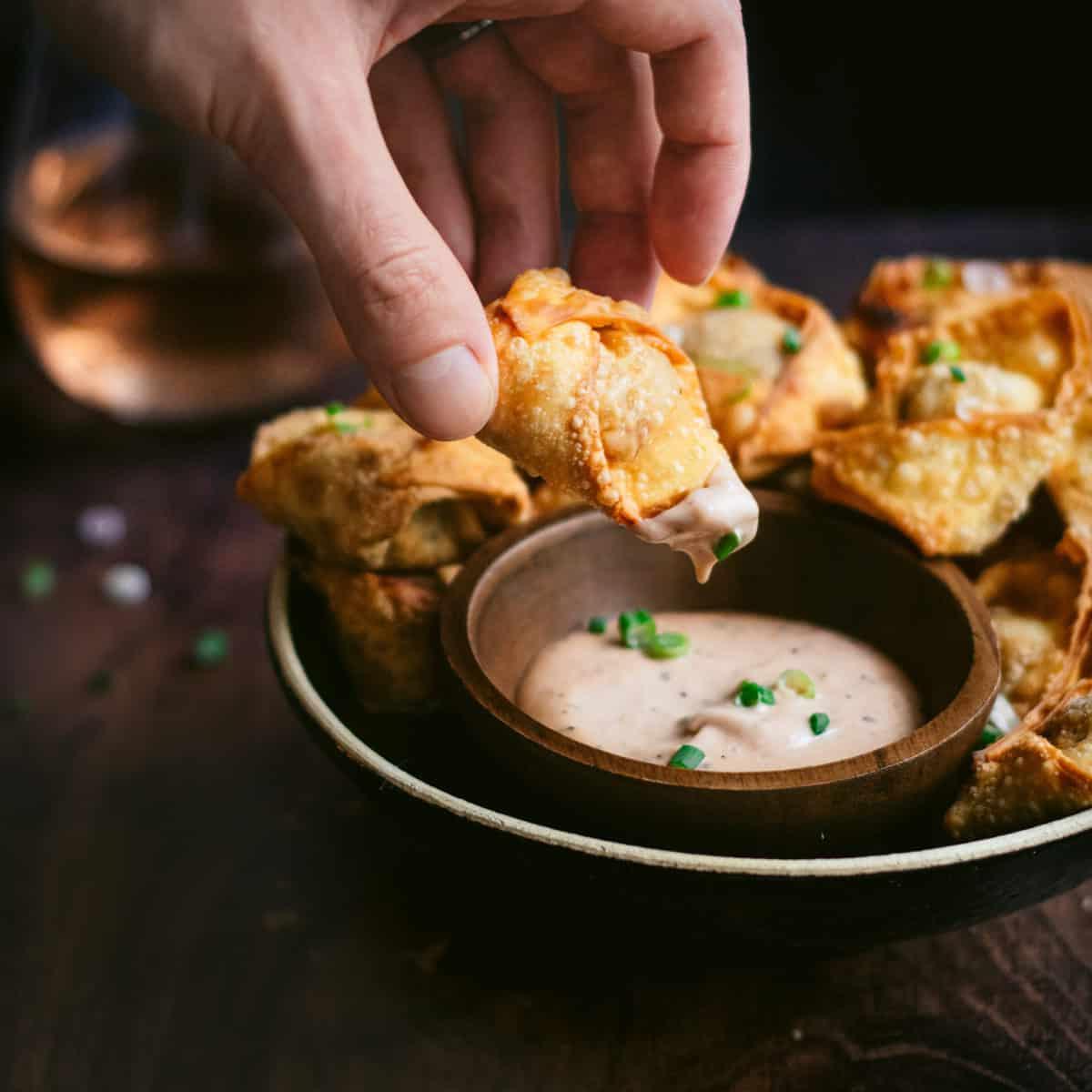 Immergere un wonton di maiale sfilacciato nella salsa