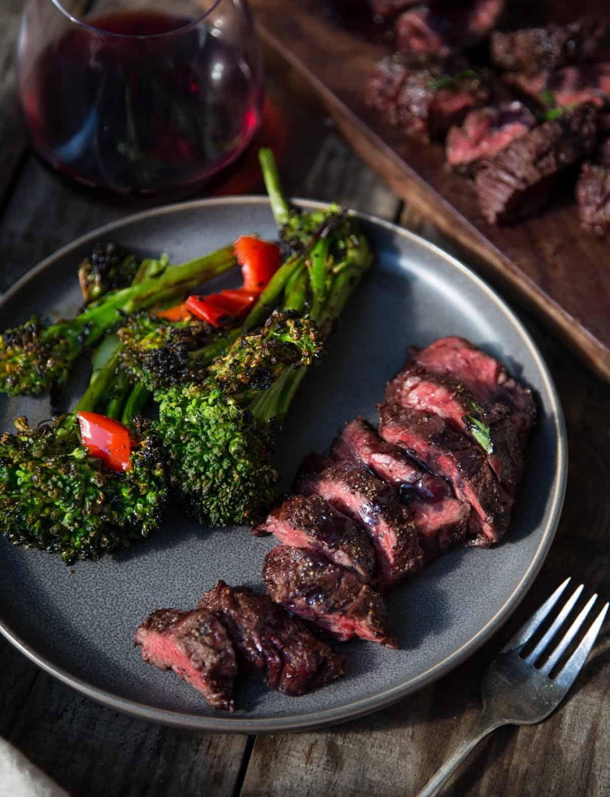 Diaframma di Manzo alla Griglia con Glassa al Pinot Nero e Marionberry 8 Un piatto con carne alla griglia e un contorno di broccolini