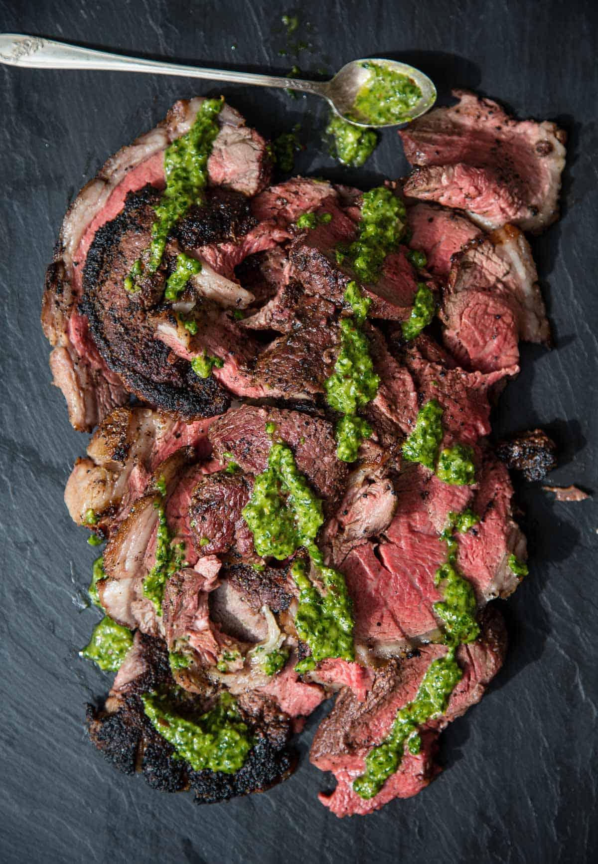 Fette di Picanha alla griglia condite con salsa chimichurri.