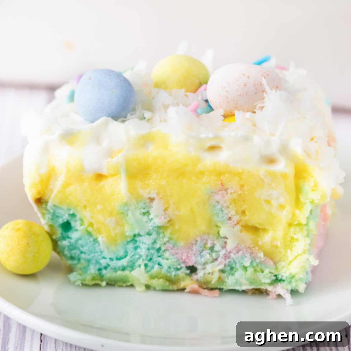 A slice of pastel Easter poke cake topped with whipped cream, coconut, and mini chocolate eggs.
