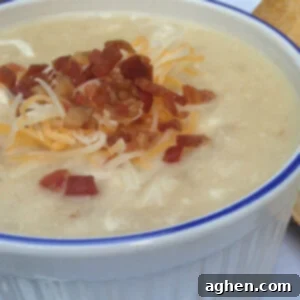 Velvety Cheesy Potato and Cauliflower Soup 2 Close-up of a rustic bowl of creamy potato and cauliflower soup, topped with melted cheese.