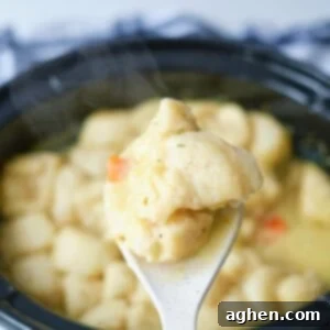 spoonful of slow cooker chicken and dumplings, showing the creamy texture and biscuit