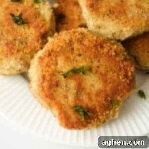Lemon-Dill Tuna Cakes 2 Crispy golden-brown tuna cakes on a paper plate, drizzled with lemon dill sauce and garnished with fresh dill.