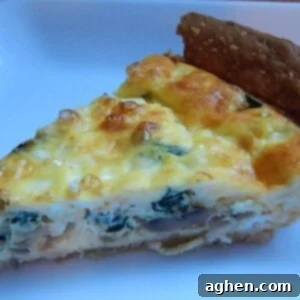 A delicious slice of spinach, mushroom, and asiago quiche ready to be served