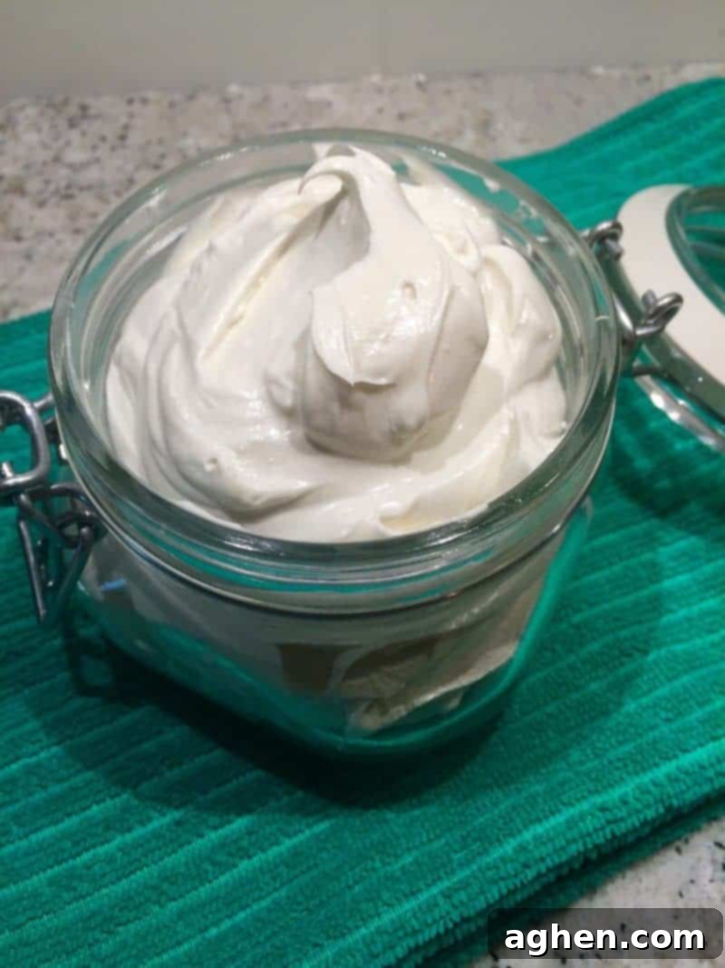 Finished DIY whipped body butter, light and fluffy in texture, stored beautifully in a clear glass jar on a wooden surface.