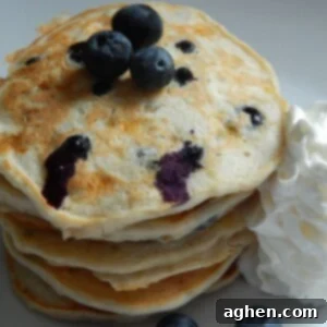 Close-up of fluffy blueberry banana pancakes on a griddle, showing golden brown edges and visible blueberries
